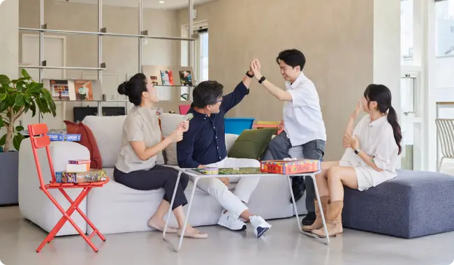 소파에서 보드게임을 하며 동료들과 웃고 있는 모습